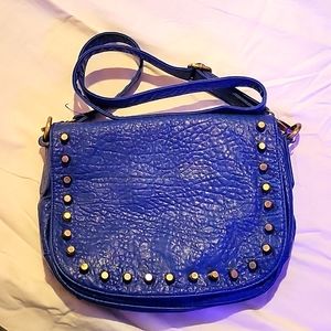 Blue leatherette crossbody bag with brass spikes and hardware.
